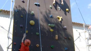 Monitores de Siberiactiva guian a dos peques durante su escalada en el rocódromo.