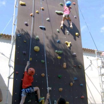 Monitores de Siberiactiva guian a dos peques durante su escalada en el rocódromo.